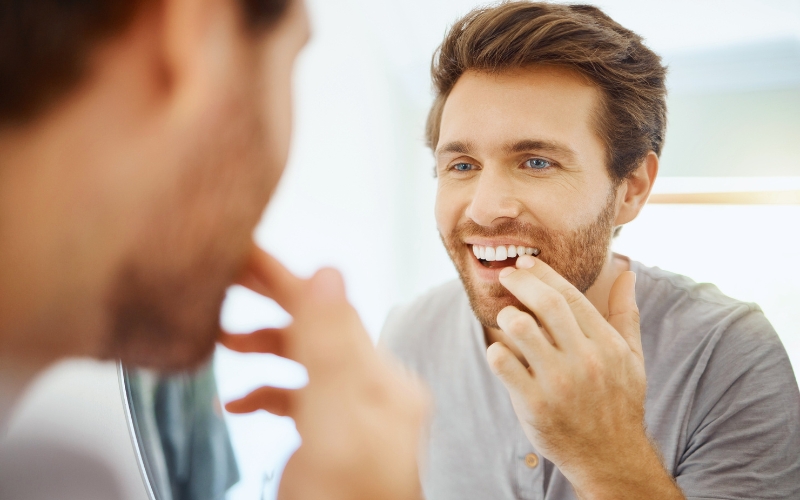 Giovane ragazzo che si guarda allo specchio i denti