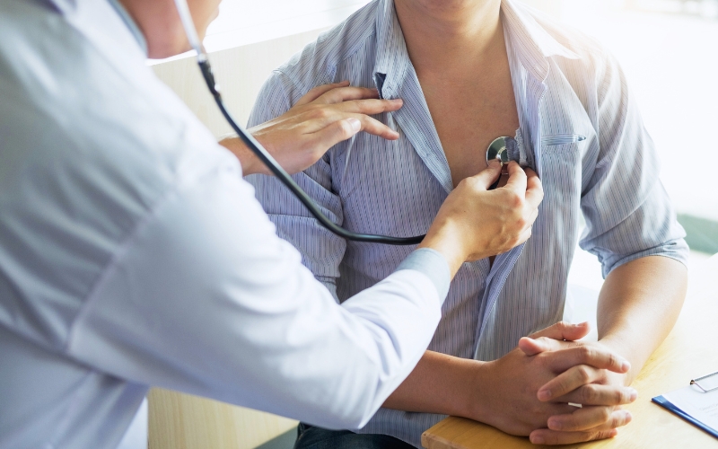 Primo piano su medico che osculta il cuore a un paziente uomo