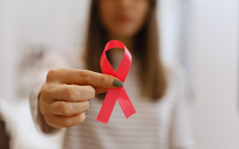 Una donna tiene in mano un nastro rosa, simbolo internazionale della lotta e della prevenzione contro il tumore al seno