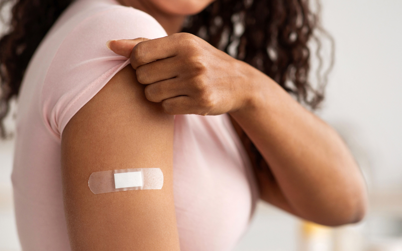 Focus sul braccio di una ragazza che si è appena sottoposta a vaccinazione. Sul braccio è stato applicato un cerotto